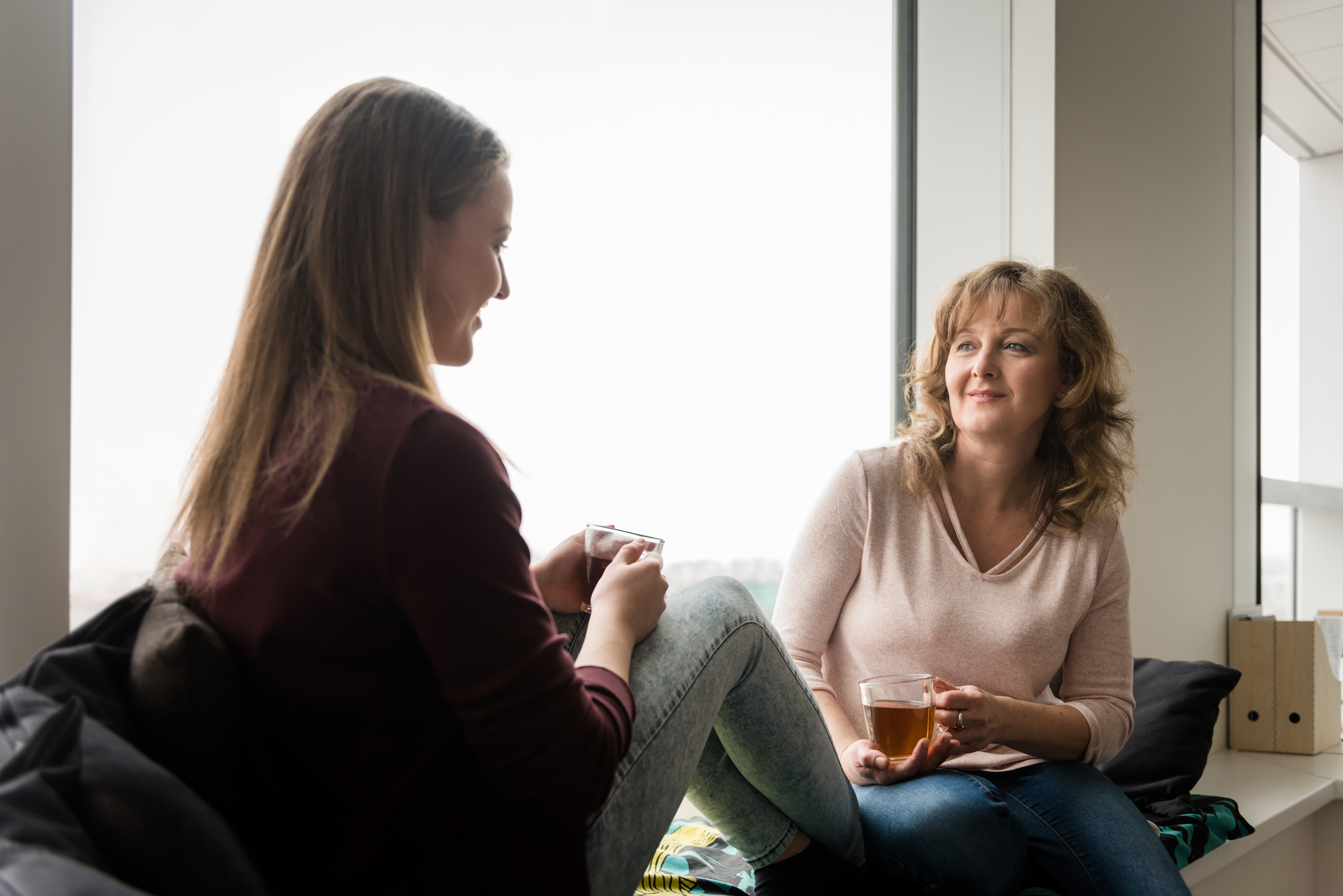 Mother talking to her daughter while having tea at home